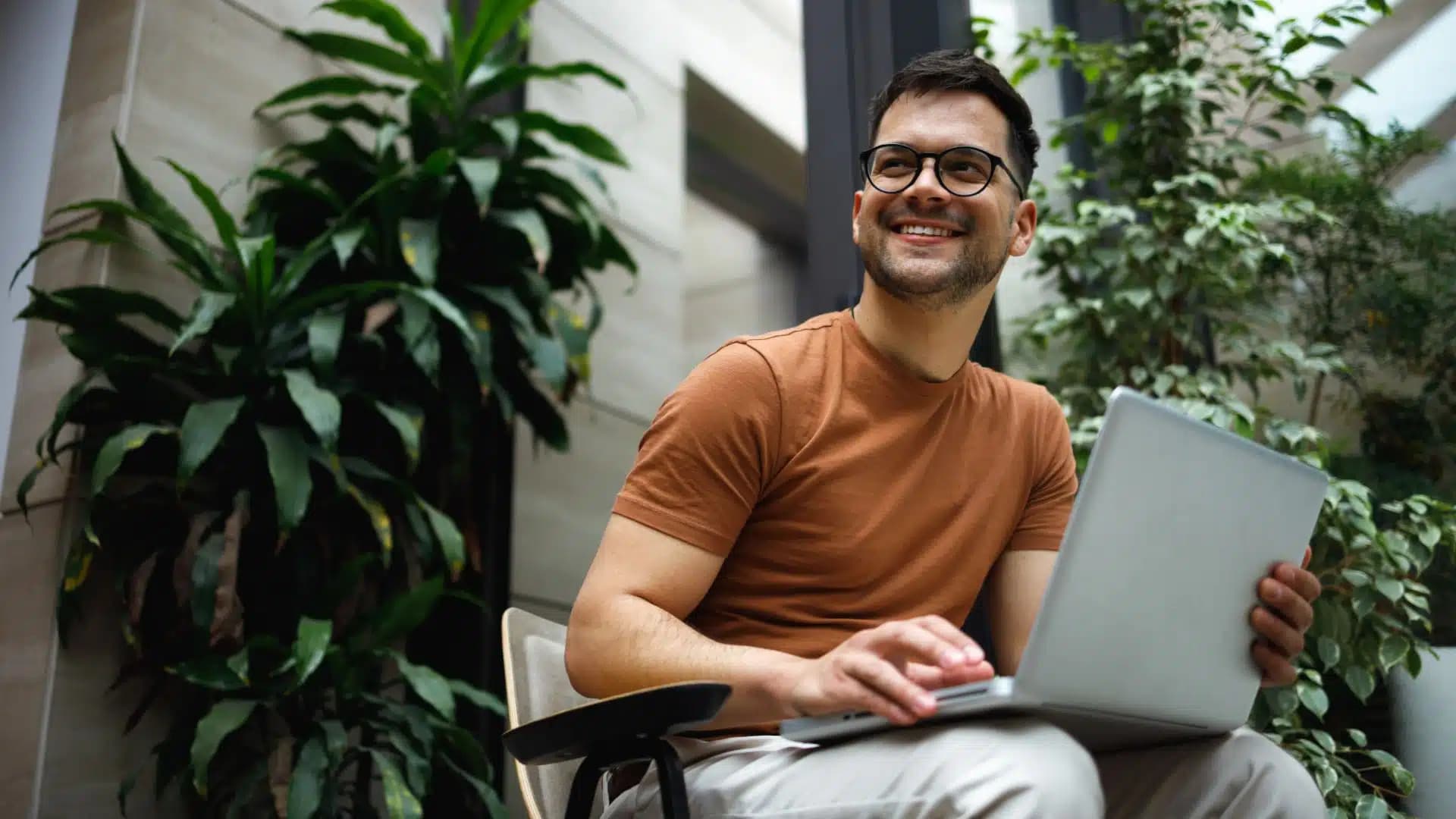 Man with glasses holding a laptop
