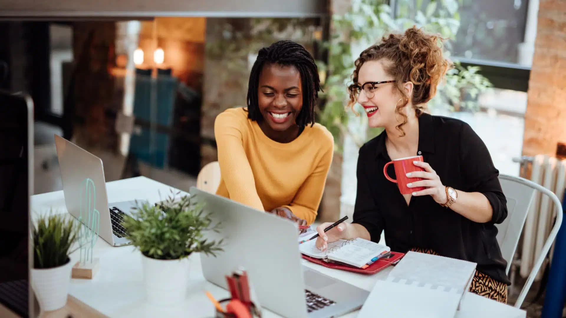 Two women looking at a laptop smiling