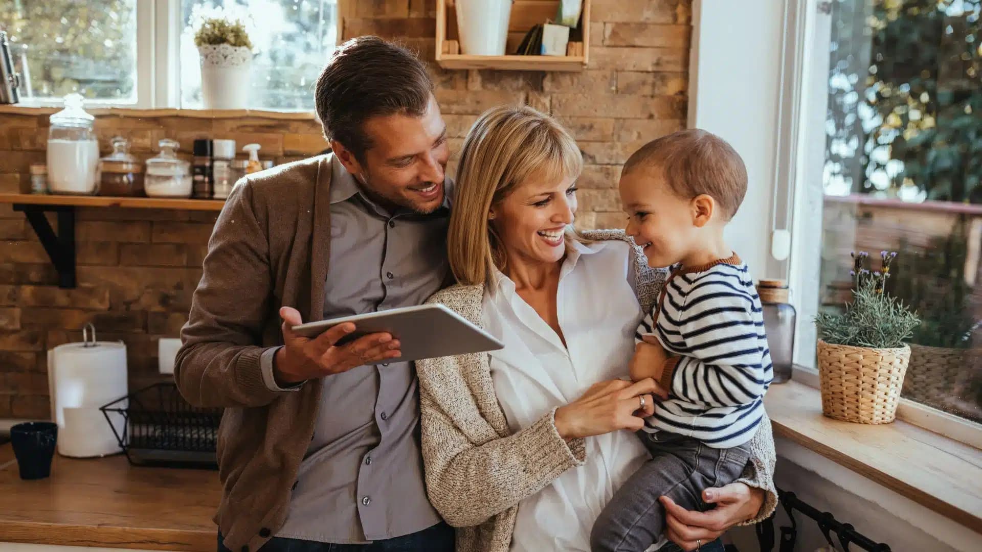 A man, woman and child smiling in a kitchen